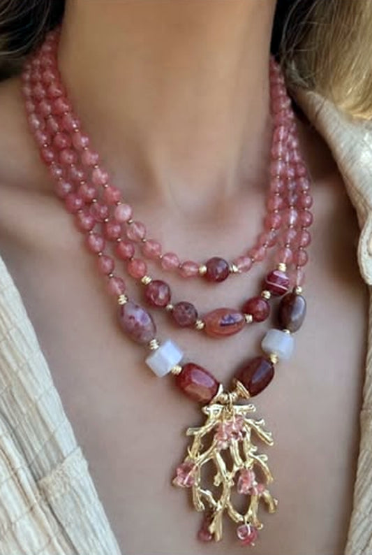 Three-strand dusty rose beaded necklace with a gold coral-branch pendant hung with pink drops